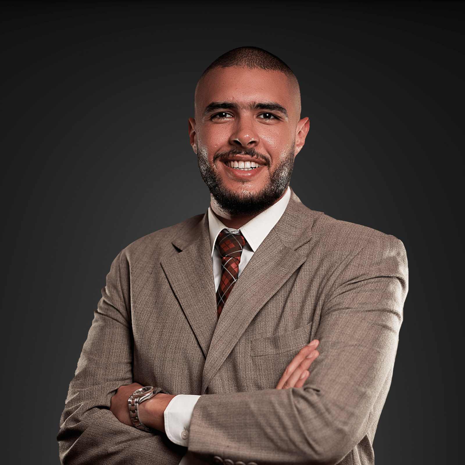 a man wearing wearing a suit with a shaved head, bearded and tall